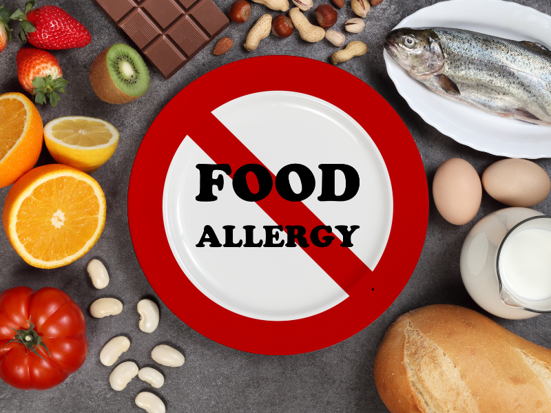 Assorted foods like fish, eggs, nuts, fruit, and milk surrounding a plate labeled “Food Allergy” with a red no symbol